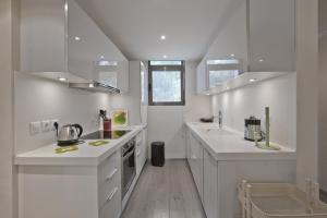 a white kitchen with white counters and white cabinets at Sea Breeze Spacious Apt near Vouliagmeni Beach in Athens