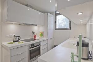 a white kitchen with a sink and a stove at Sea Breeze Spacious Apt near Vouliagmeni Beach in Athens +16 photos