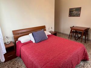 a bedroom with a bed with a red blanket and a table at Bed and Breakfast Elisa in Sonnino
