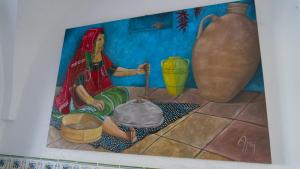 a painting of a woman sitting on the floor next to a vase at Dar El Goulli in Sousse