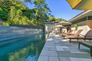 uma piscina com mesas e cadeiras ao lado de uma casa em 7403 Peaceful 5 Star Noosa em Noosa Heads