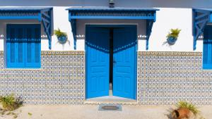 niebieskie drzwi na białym budynku z niebieskimi oknami w obiekcie Dar El Goulli w Susie