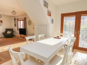 a white dining room with a white table and chairs at Siena in Kilgetty