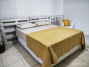 a large bed with a yellow blanket on top of it at Casa espaçosa próxima ao centro in Encantado