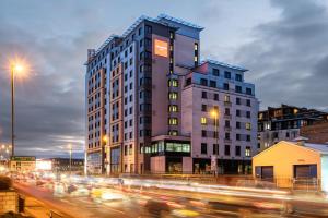 a tall building on a busy city street with traffic at Leonardo Hotel Nottingham in Nottingham