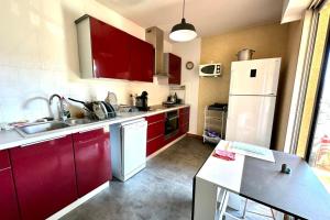 uma cozinha com armários vermelhos e um frigorífico branco em Luminous cocoon in the heights of Ajaccio em Ajaccio