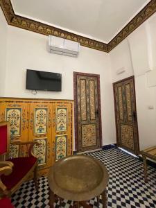 Habitación con 2 puertas, mesa y TV. en Riad Shama Fes en Fez