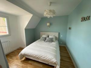 a bedroom with a bed with white sheets and a chandelier at Maison cosy en plein coeur de Ouistreham in Ouistreham