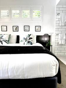 una camera da letto con un grande letto con lenzuola e cuscini bianchi di 225 2 Bedroom Garden Oasis French Quarter Resort a Noosa Heads