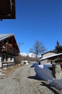 een geplaveide straat met sneeuw op de grond naast gebouwen bij Casa Griot in Pragelato