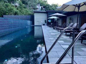 a swimming pool with some chairs and an umbrella at 9311 Fabulous Resort in the Heart of Noosa in Noosa Heads