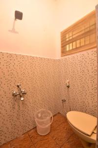 a bathroom with a toilet and a fan on the wall at Villa Felicia in Pondicherry