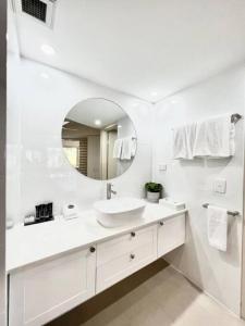 Baño blanco con lavabo y espejo en 124 Hastings Street 2 bedroom walk to the beach, en Noosa Heads