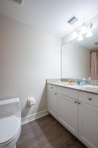 a bathroom with a sink and a toilet and a mirror at Updated Beach Condo! Facing Heated Pool & Sunset! in Naples