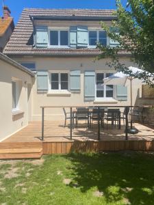 a patio with tables and umbrellas in front of a house at Maison cosy en plein coeur de Ouistreham in Ouistreham