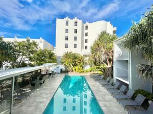 uma piscina com cadeiras e um edifício em 6Apt Beautifully renovated on Hastings Street em Noosa Heads