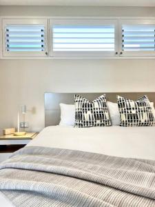 1 dormitorio con 1 cama con almohadas a cuadros en 6Apt Beautifully renovated on Hastings Street en Noosa Heads