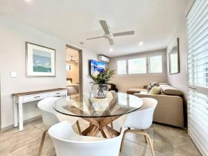 a dining room with a glass table and white chairs at 6Apt Beautifully renovated on Hastings Street in Noosa Heads