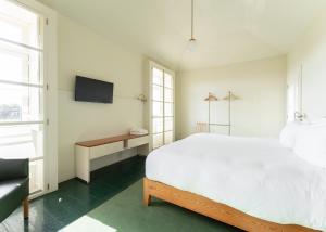 Duas Portas Townhouse في بورتو: غرفة نوم بيضاء فيها سرير وتلفزيون