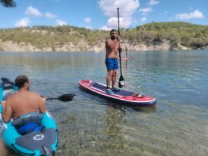 un homme debout sur une planche de paddle dans l'eau dans l'établissement Chambre privée au cœur du Verdon, à Saint-Julien