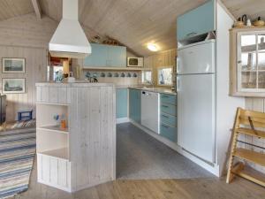 cocina con armarios azules y nevera blanca en Holiday Home Klint - 1-7km from the sea in Western Jutland by Interhome, en Fanø