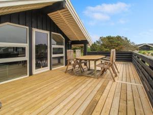 een houten terras met een tafel en stoelen erop bij Holiday Home Skyler - 1km from the sea in Western Jutland by Interhome in Fanø