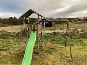 een speeltuin met een groene glijbaan in een veld bij Holiday Home Skyler - 1km from the sea in Western Jutland by Interhome in Fanø