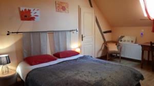 La Ferme de l'isle et sa Roulotte في Avaray: غرفة نوم بسرير كبير ومخدات حمراء