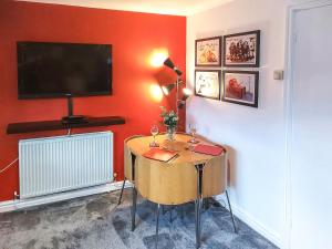 Zimmer mit einem Tisch und einem TV an einer roten Wand in der Unterkunft Bownessys Retreat - 26989 in Bowness-on-Windermere