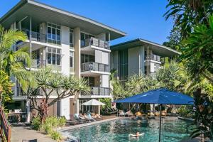 an apartment building with a pool and an umbrella at 9309 Tranquil Viridian 2 Bedroom Luxury in Noosa Heads