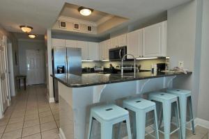 a kitchen with white cabinets and bar stools at Crystal Tower 1202 in Gulf Shores