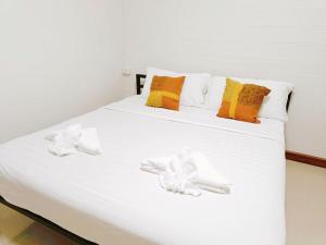 a white bed with pillows on top of it at Baan PhakDeeChan in Chanthaburi