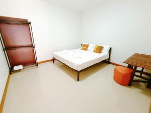 een witte kamer met een bed en een tafel bij Baan PhakDeeChan in Chanthaburi