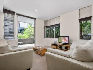 a living room with two white couches and a tv at 7211 Lovely 2 Bedroom Viridian Noosa in Noosa Heads