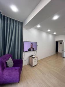 ein Wohnzimmer mit einem lila Sofa und einem Flachbild-TV in der Unterkunft 2-room apartment Centrium Residence in Bischkek
