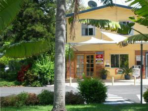 ein gelbes Gebäude mit einer Palme davor in der Unterkunft Riverside Tourist Park in Rockhampton