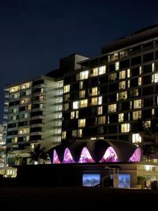 un grand bâtiment avec des lumières violettes la nuit dans l'établissement Casa Del Sol-Unit A, à Bayamon