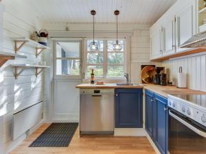 a kitchen with blue and white cabinets and a sink at Holiday Home Semund - 2km from the sea by Interhome in Sønderby +23 photos