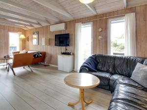 a living room with a leather couch and a table at Holiday Home Casandra - 600m from the sea in Western Jutland by Interhome in Fanø