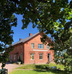 um antigo edifício de tijolos vermelhos com árvores em primeiro plano em FärgLabbets Bed and Breakfast em Sunne