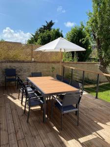 a wooden table with chairs and an umbrella on a deck at Maison cosy en plein coeur de Ouistreham in Ouistreham