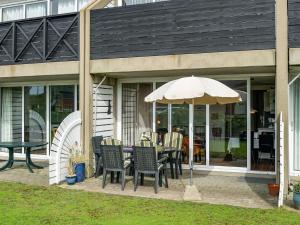 a patio with a table and chairs and an umbrella at Apartment Iliane - 100m from the sea in Western Jutland by Interhome in Fanø