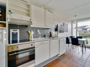 una cucina con armadi bianchi e tavolo con sedie di Apartment Iliane - 100m from the sea in Western Jutland by Interhome a Fanø