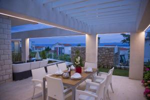 a patio with a wooden table and white chairs at Villa Dalmatina - Adults Only in Bol