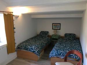 um pequeno quarto com 2 camas e uma cadeira em Maison de village et jardin , à Mornac sur Seudre em Mornac-sur-Seudre