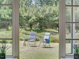duas cadeiras sentadas no pátio vistas através de uma janela em Holiday Home Hakun - 4km from the sea in Western Jutland by Interhome em Rømø Kirkeby