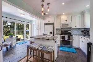 a kitchen with white cabinets and a island with bar stools at Bluebird Bungalow in Jacksonville