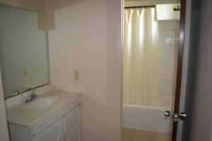 La salle de bains blanche est pourvue d'un lavabo et d'une douche. dans l'établissement Lighthouse Motel, à Walkerton