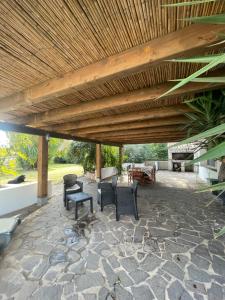 un patio con techo de madera, sillas y mesa en Roy House, en Alghero