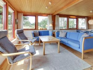een woonkamer met een blauwe bank en stoelen bij Holiday Home Sweni - 800m from the sea in Western Jutland by Interhome in Fanø